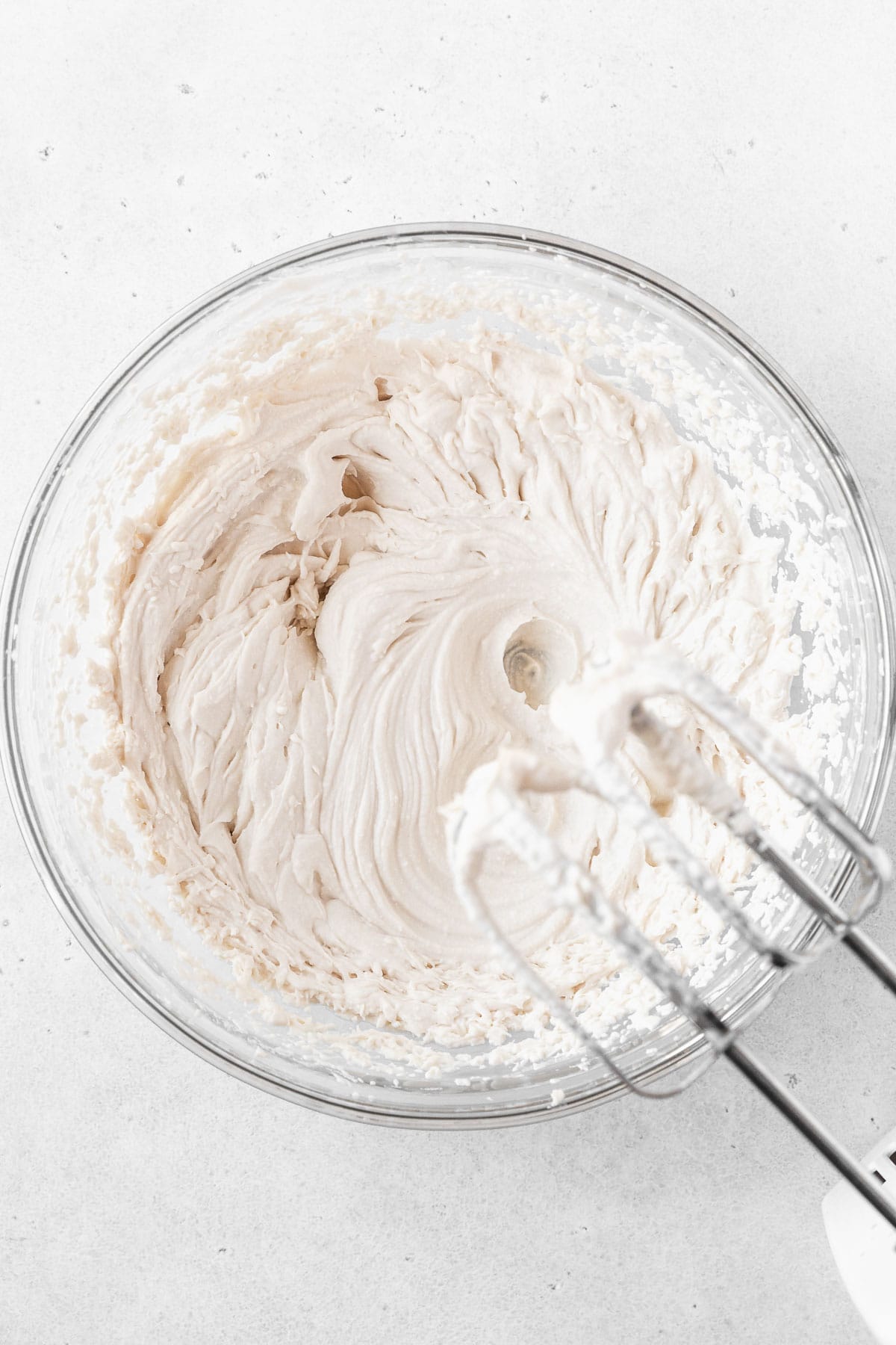 Whipping up oat milk whipping cream in a glass mixing bowl.
