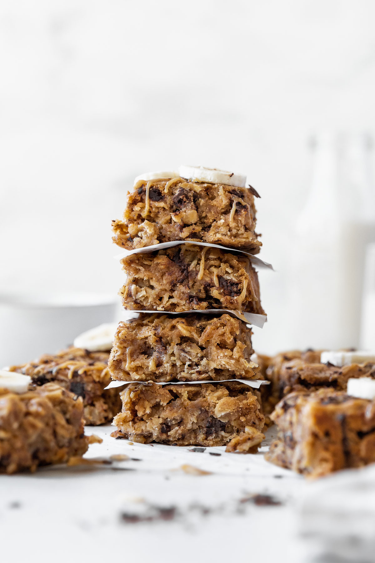 A side shot of a stack of peanut butter oatmeal breakfast bars on the counter with other bars in the background.