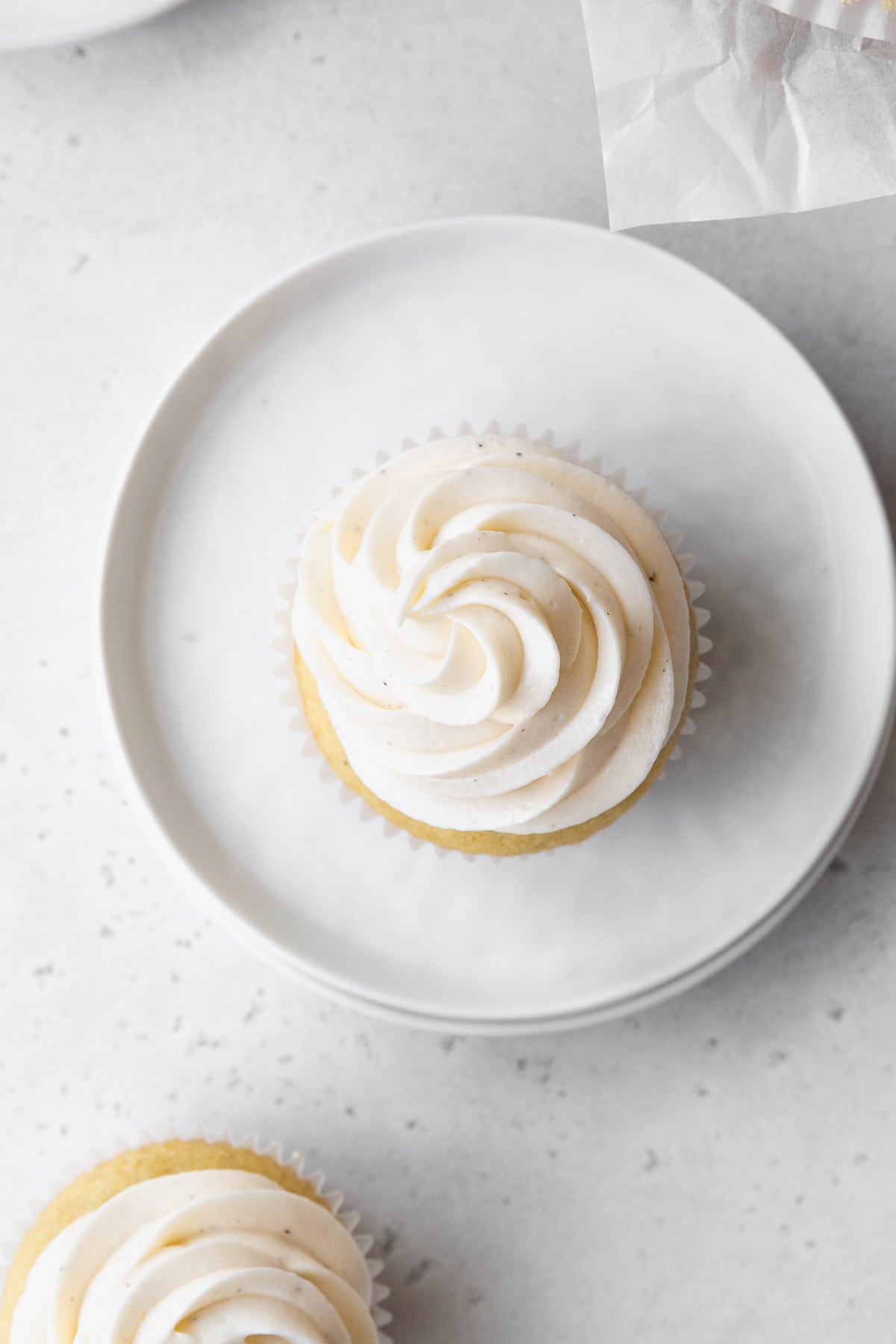 Overhead shot of a vanilla cupcake topped with vegan vanilla buttercream frosting.