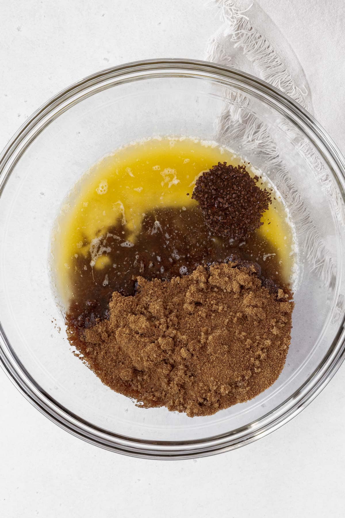 Melted butter, chocolate, sugar, and espresso powder in a glass mixing bowl.