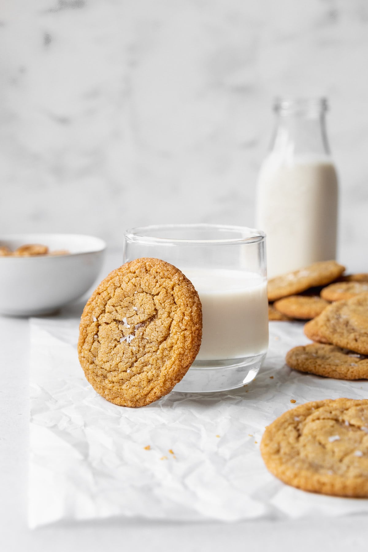 A dairy-free peanut butter cookie resting on a glass of milk.