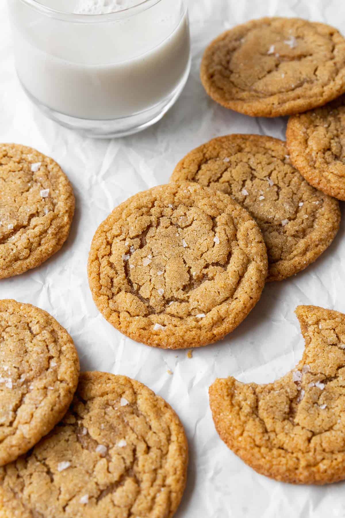 An up-close shot of the dairy free peanut butter cookies on parchment paper. One of the cookies has a bite taken out of it. 