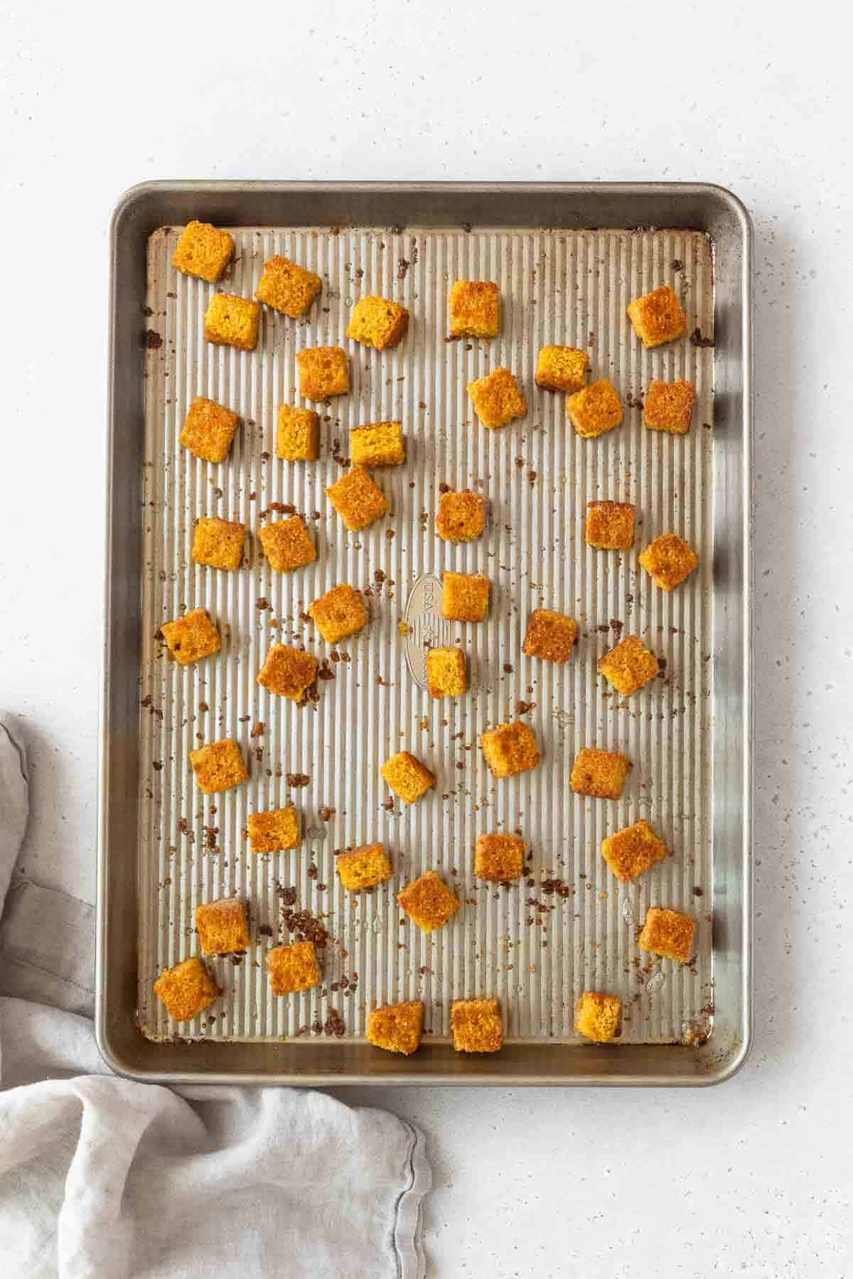 Toasted cornbread croutons on a baking sheet.