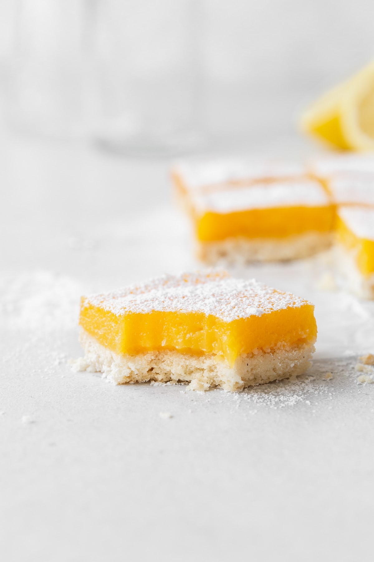 A side shot of a dairy-free lemon bar with a bite taken out of it.