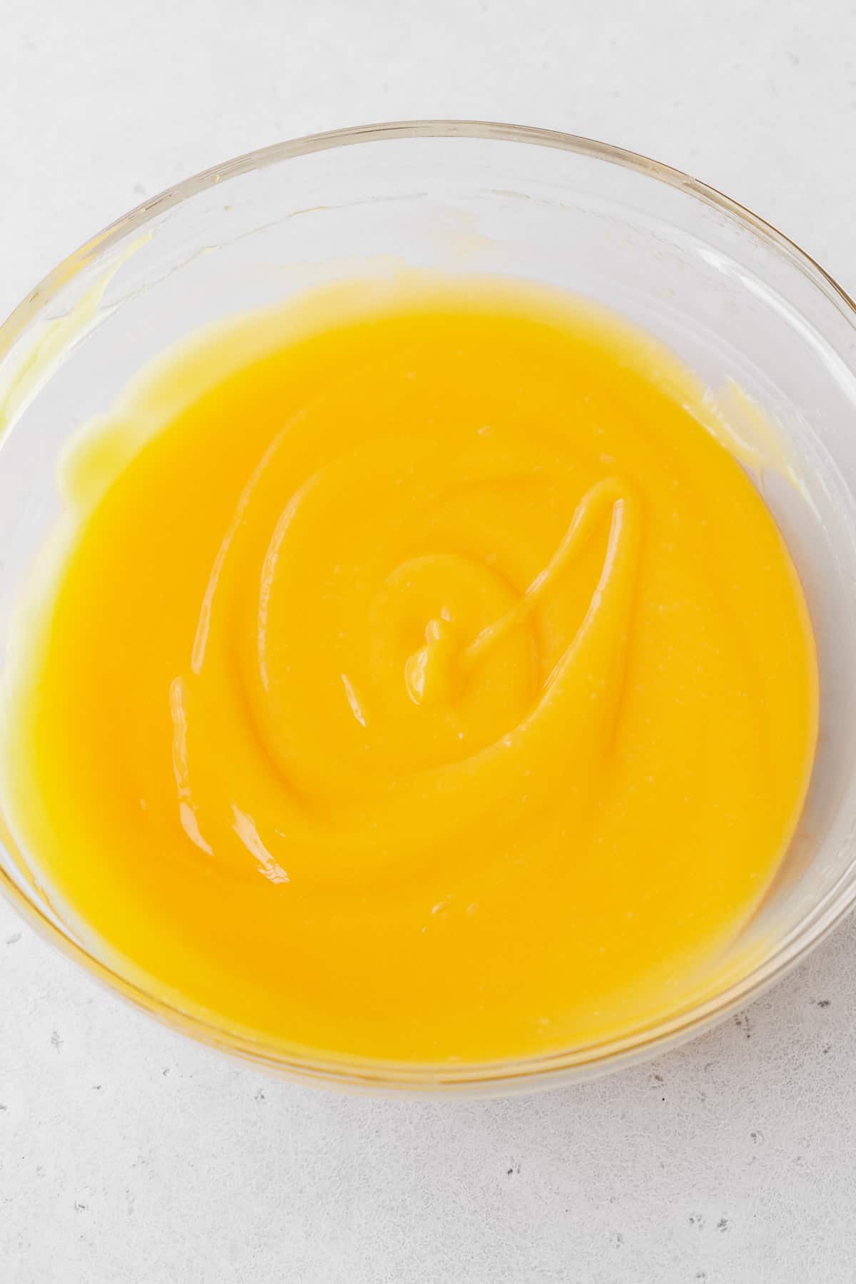 The lemon curd filling whisked up in a glass mixing bowl.