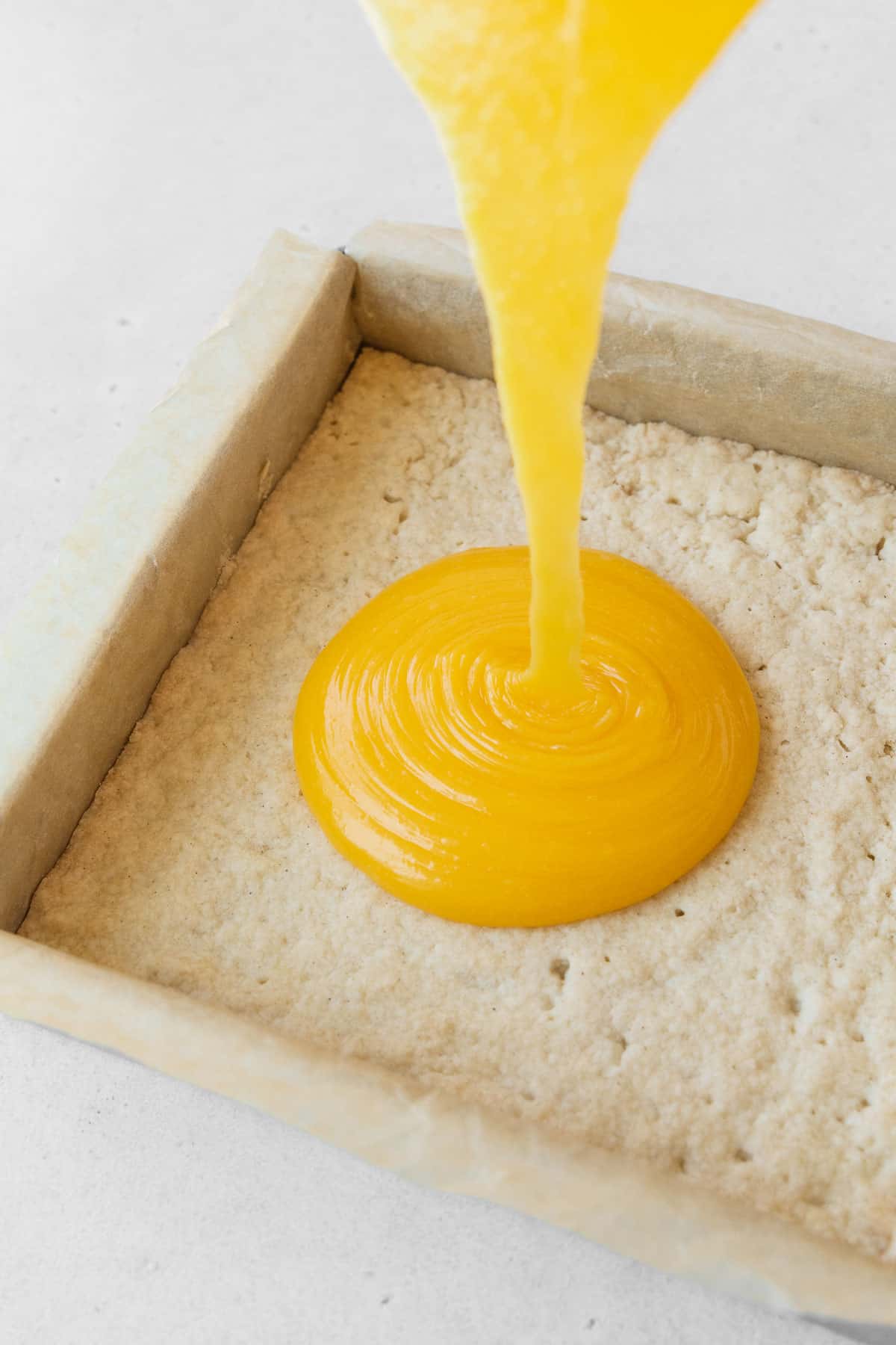 Pouring the dairy-free lemon curd filling onto the shortbread crust.