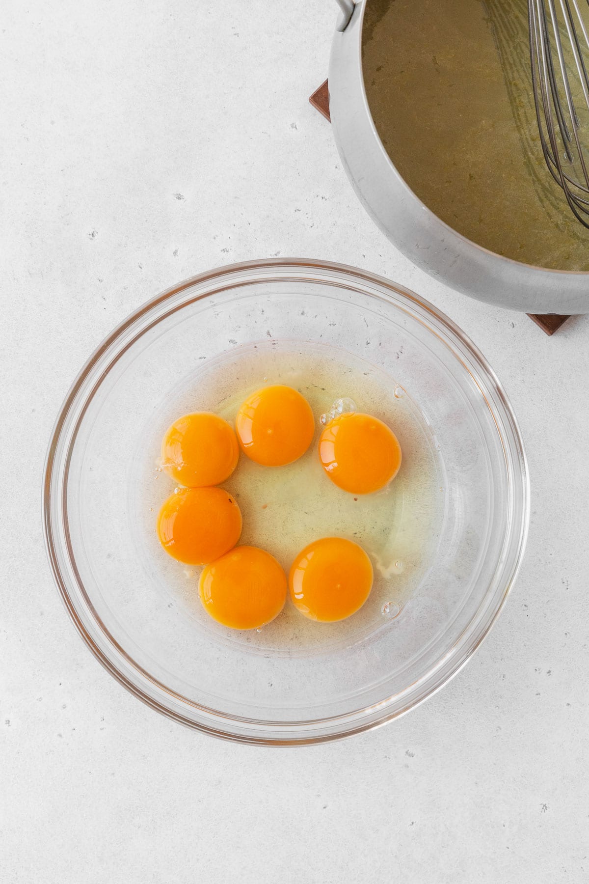 6 egg yolks in a glass mixing bowl on the counter.