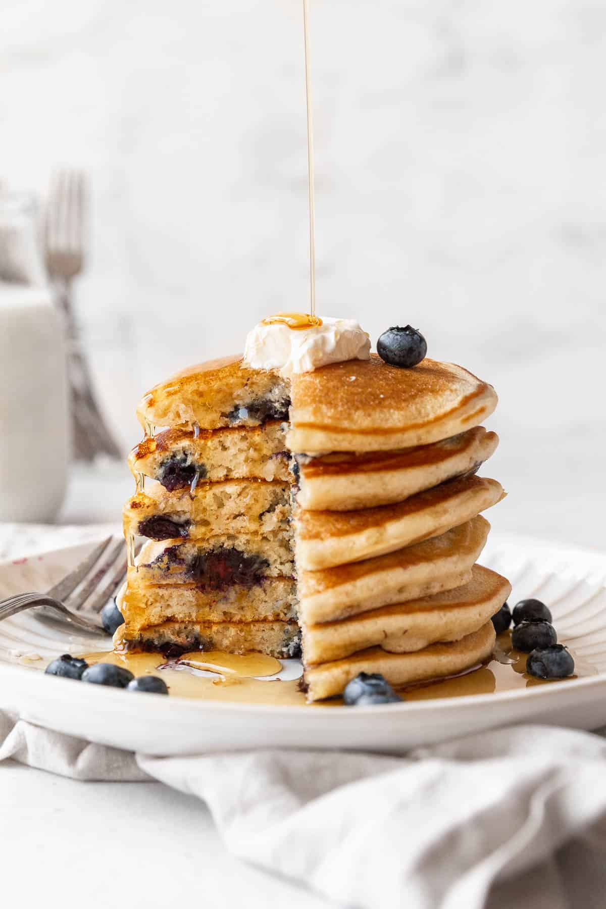 Side-on shot of a stack of muffin mix blueberry pancakes with a quarter of the tower removed to show the fluffy interior.