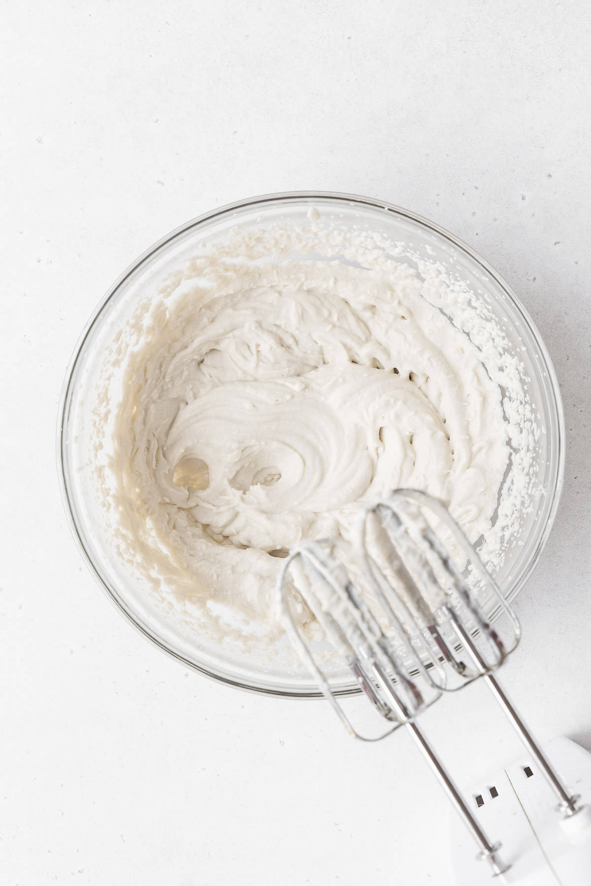 Whipping the non-dairy whipped cream in a glass mixing bowl.