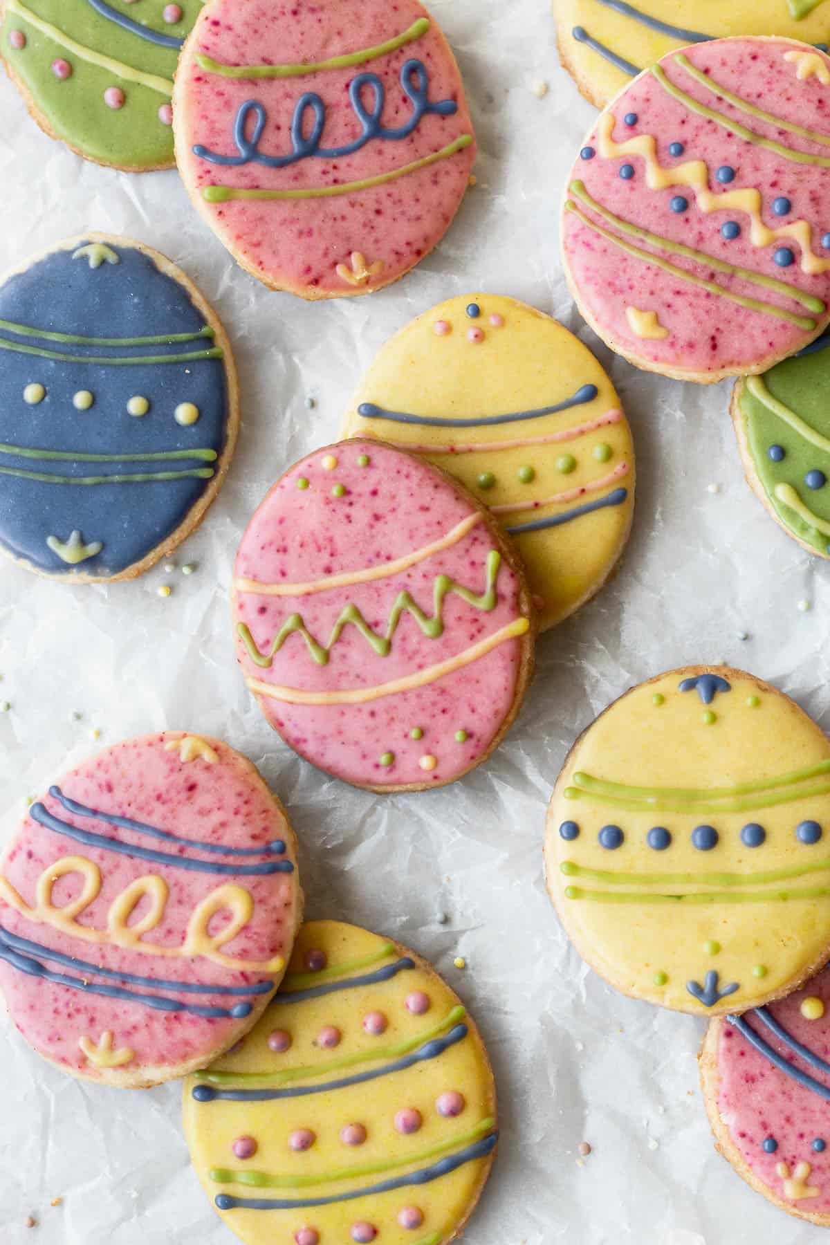 Easter egg sugar cookies decorated with different colored icing on parchment paper.