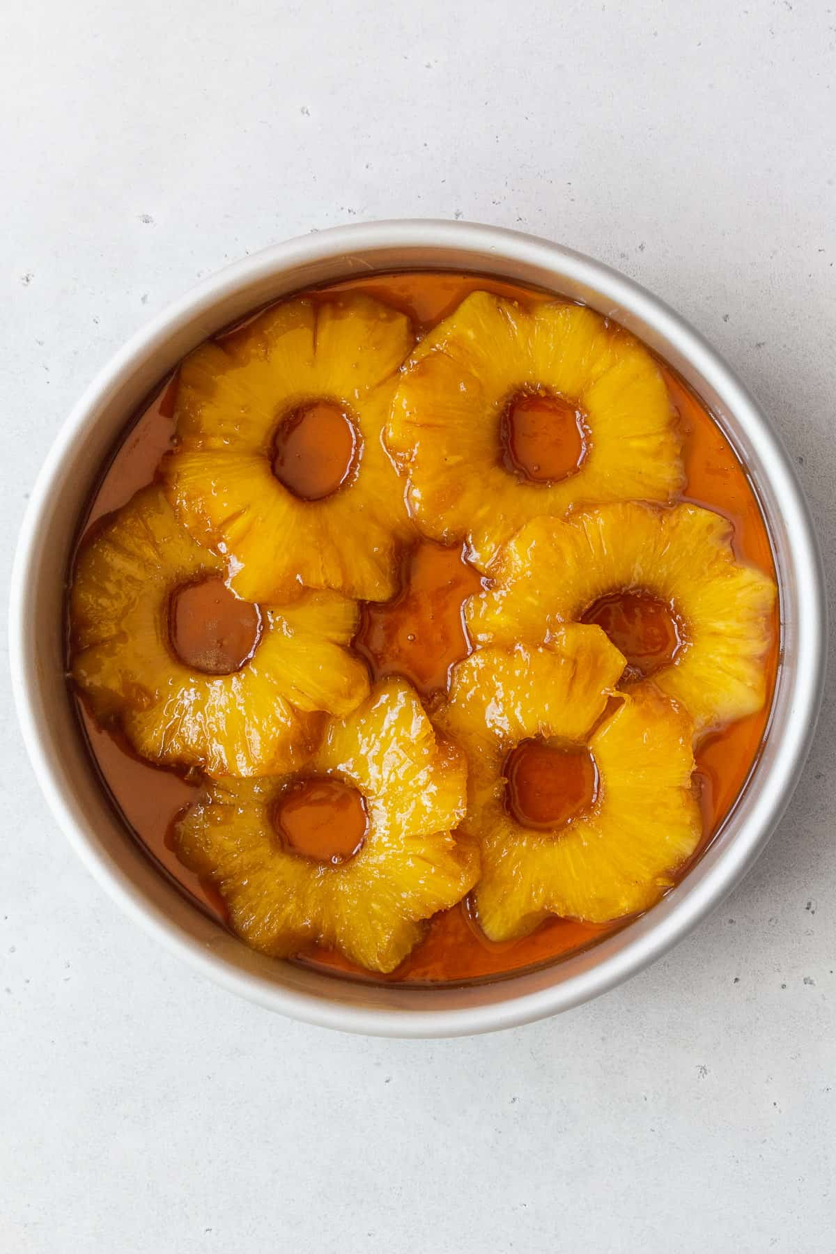 A cake pan of the brown sugar butter and pineapple rings in it.