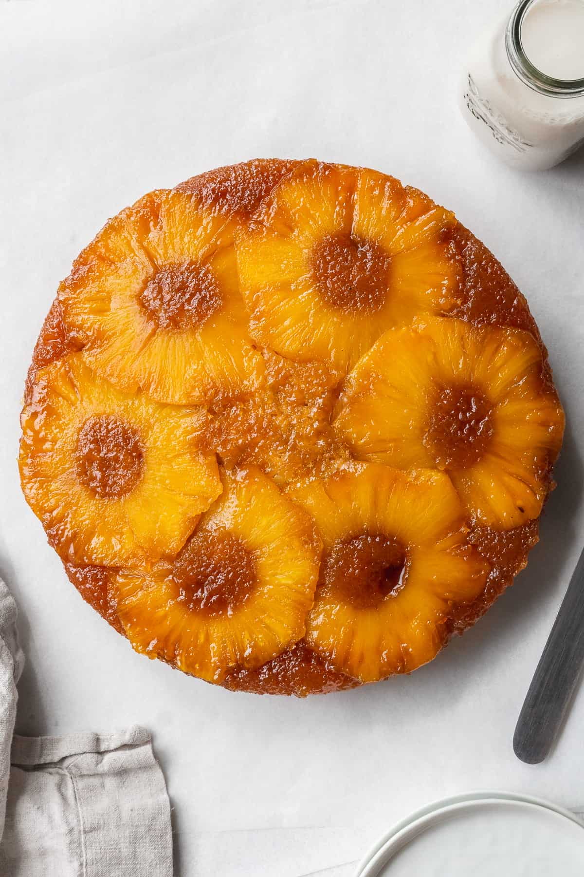 Pineapple upside down cake on the counter with napkins, a small bottle of milk.