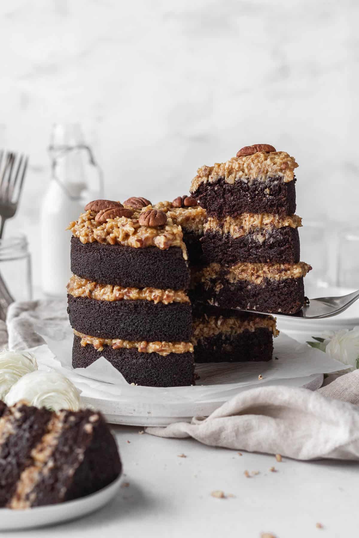 A gluten-free German chocolate cake with a slice being taken out.