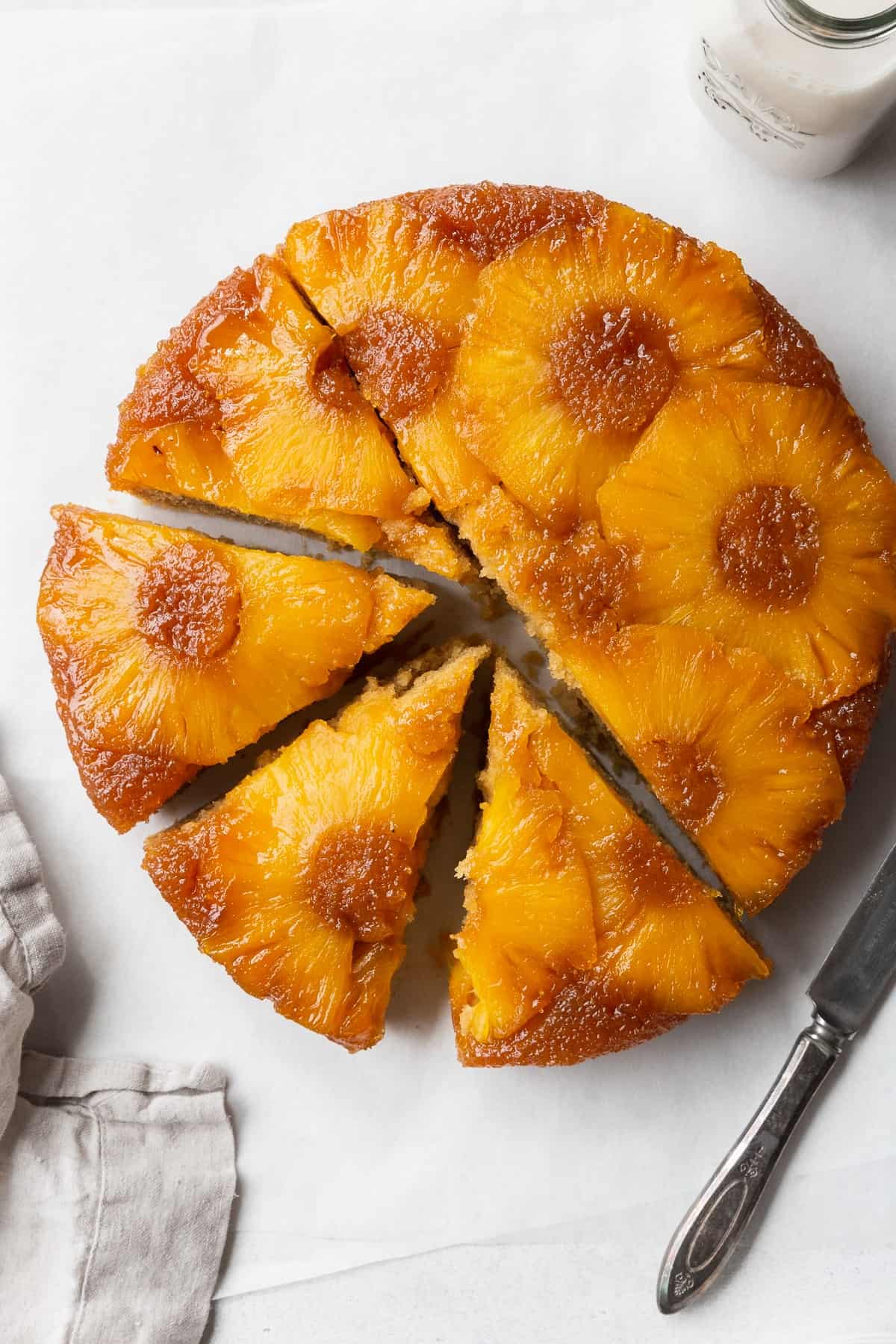 Sliced gluten-free pineapple upside down cake on the counter with a napkin and knife.
