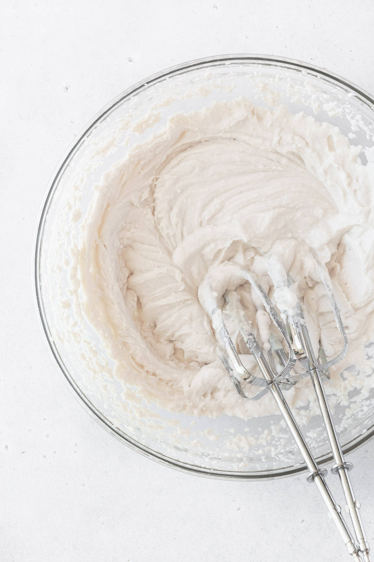 A bowl of vegan whipped cream with two beaters placed inside.