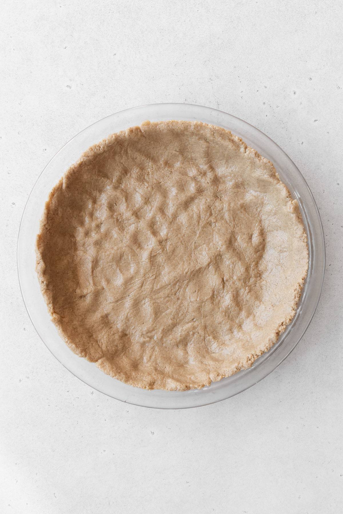 Oatmeal crust dough pressed into a glass pie dish.