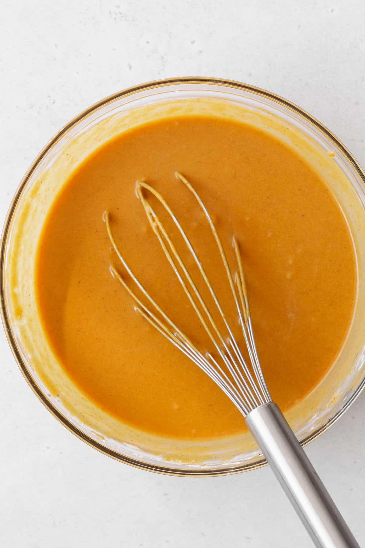 Vegan pumpkin pie filling in a bowl with a whisk.