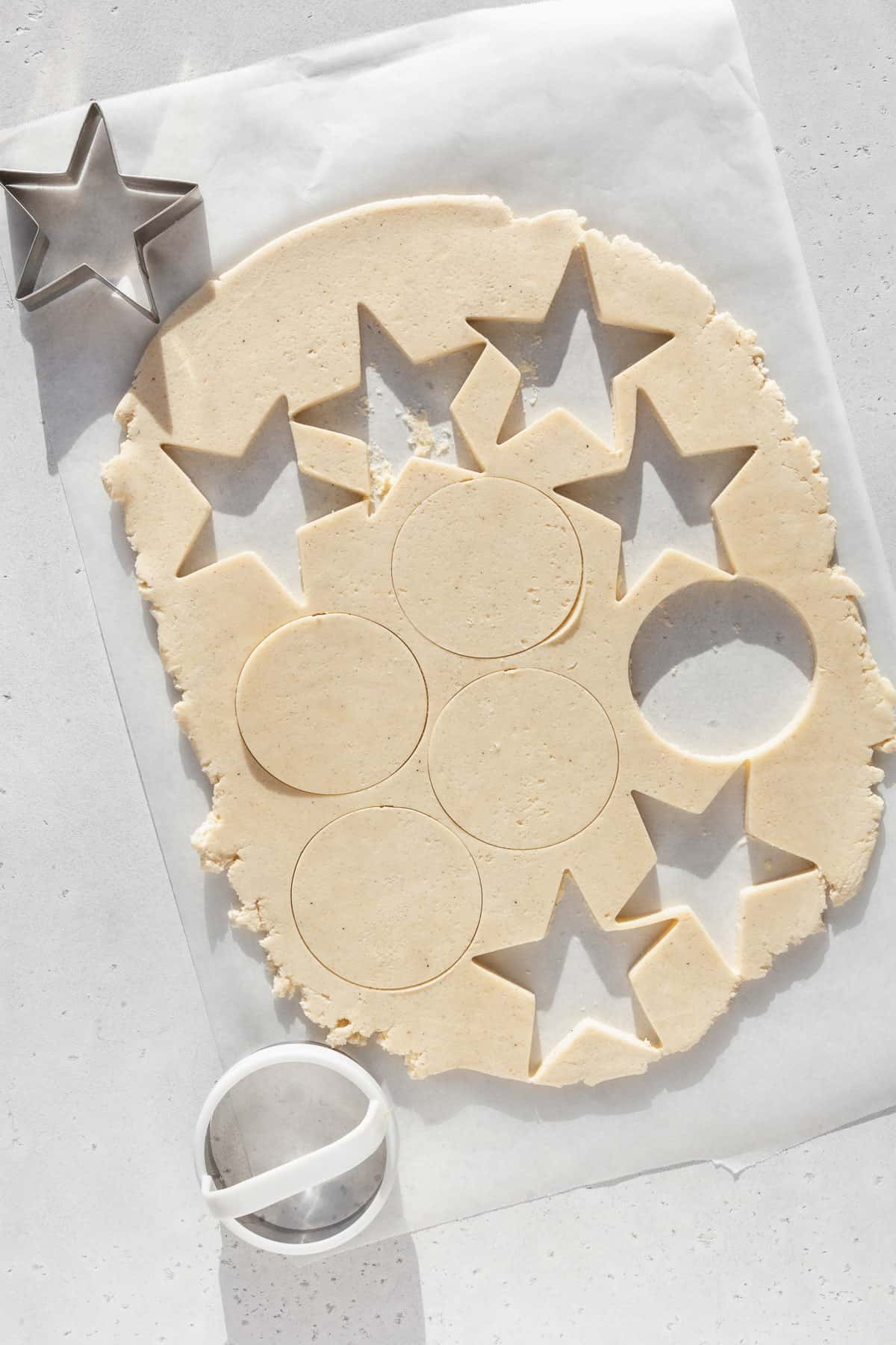 Shapes being cut out of rolled out sugar cookie dough.