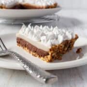 A slice of chocolate haupia pie on a white plate with a silver spoon.